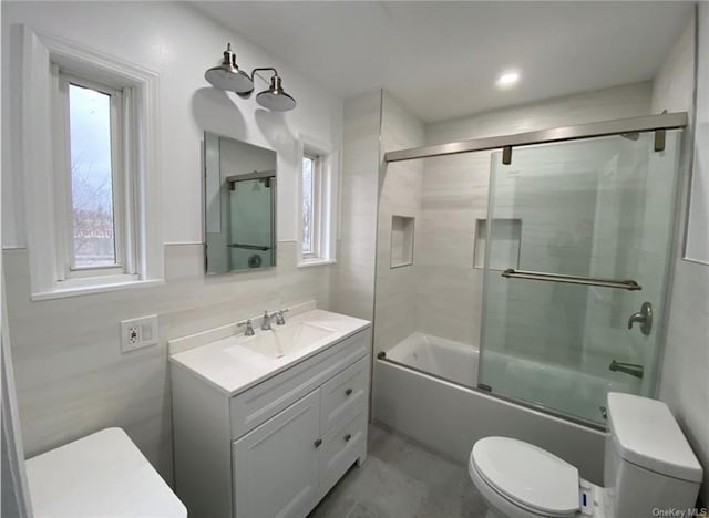 full bath with vanity, toilet, a healthy amount of sunlight, and enclosed tub / shower combo