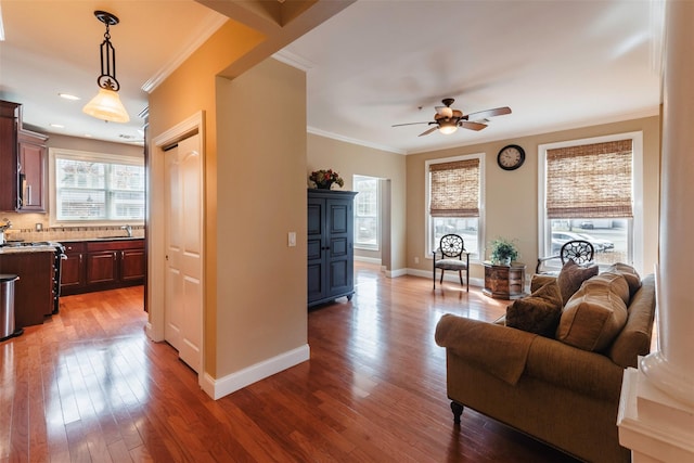 living room with baseboards, ceiling fan, ornamental molding, and light wood finished floors