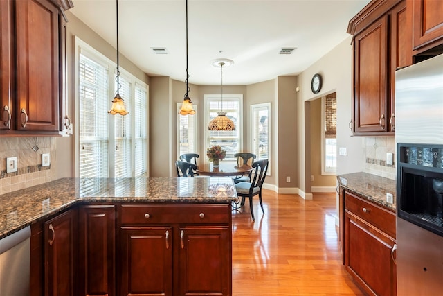 kitchen featuring light wood-type flooring, stainless steel appliances, visible vents, and a peninsula