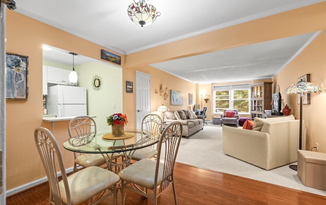 dining area featuring ornamental molding, baseboards, and wood finished floors