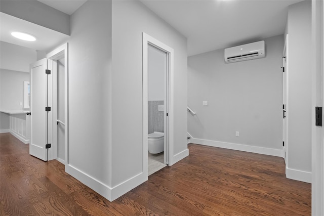 corridor with baseboards, an AC wall unit, and dark wood-style flooring