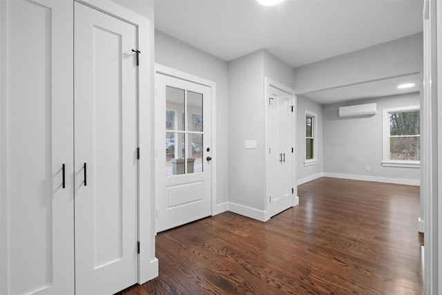 foyer featuring dark wood finished floors, an AC wall unit, and baseboards