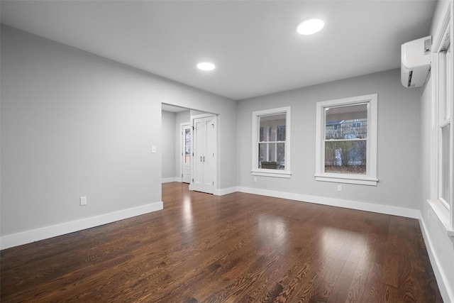 spare room with recessed lighting, baseboards, dark wood-style flooring, and a wall unit AC