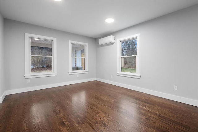 spare room with baseboards, dark wood finished floors, and a wall unit AC