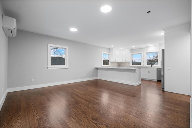 unfurnished living room with recessed lighting, a wall mounted AC, dark wood-type flooring, and baseboards