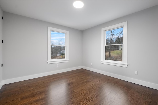 unfurnished room featuring baseboards, plenty of natural light, and dark wood finished floors