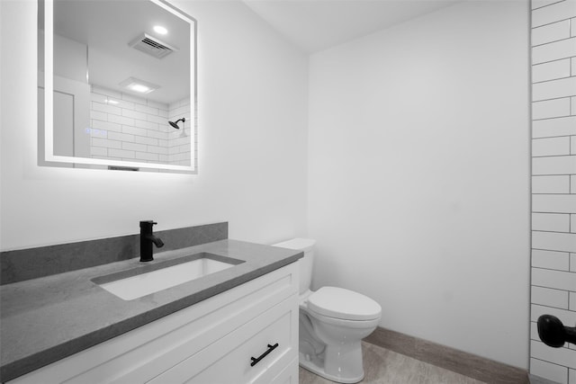 full bathroom with vanity, toilet, visible vents, and tiled shower