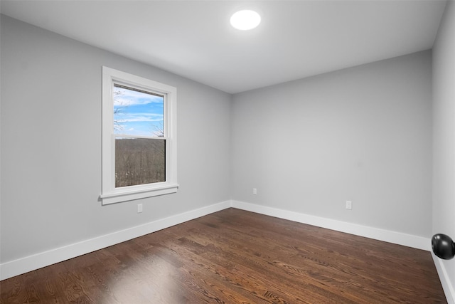 spare room with dark wood-type flooring and baseboards