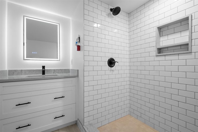 full bathroom featuring tiled shower and vanity