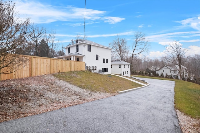 view of side of home with fence, a lawn, and driveway