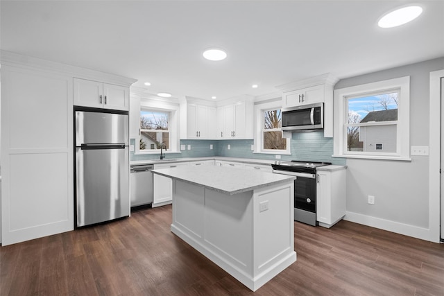 kitchen featuring dark wood finished floors, decorative backsplash, white cabinets, stainless steel appliances, and a sink