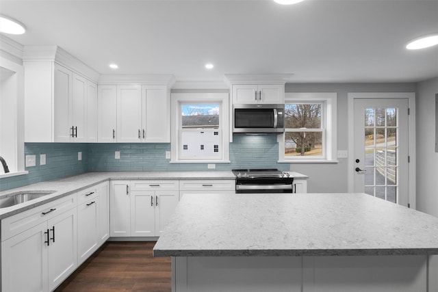 kitchen featuring dark wood finished floors, a sink, appliances with stainless steel finishes, backsplash, and a center island