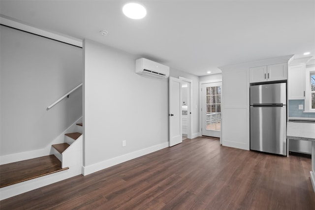 interior space with a wall mounted AC, backsplash, dark wood finished floors, white cabinetry, and stainless steel appliances