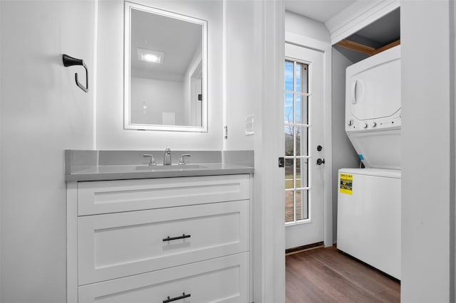 bathroom featuring wood finished floors, vanity, and stacked washer / dryer