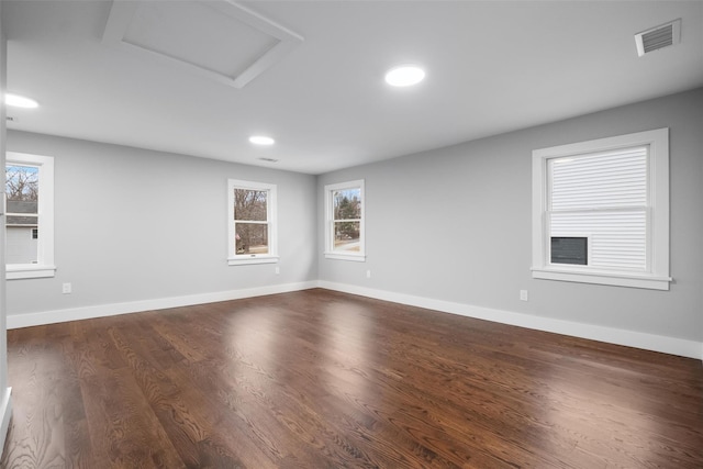 spare room with visible vents, dark wood-type flooring, recessed lighting, baseboards, and attic access