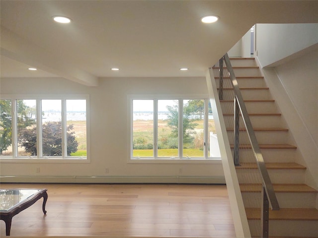 staircase with recessed lighting, wood finished floors, and a healthy amount of sunlight