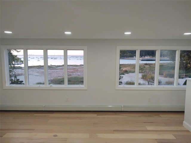 spare room featuring recessed lighting, a water view, and light wood-type flooring