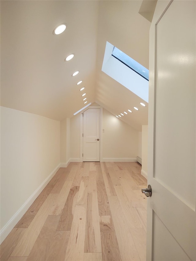 additional living space featuring lofted ceiling with skylight, recessed lighting, light wood-style flooring, and baseboards