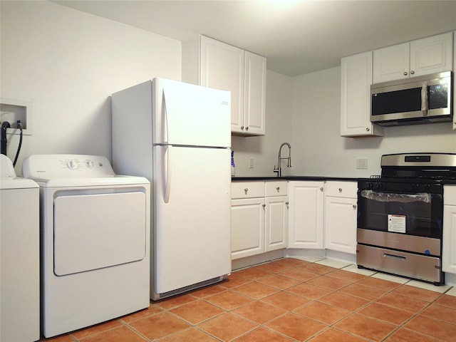 kitchen with appliances with stainless steel finishes, white cabinets, light tile patterned flooring, washer and dryer, and a sink