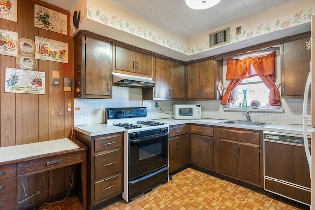 kitchen with a sink, under cabinet range hood, range with gas cooktop, white microwave, and dishwasher