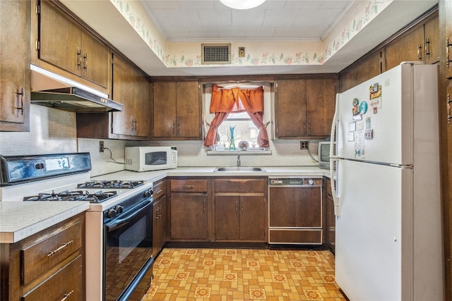 kitchen with visible vents, under cabinet range hood, light countertops, white appliances, and a sink