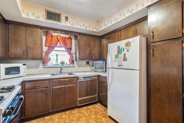 kitchen featuring visible vents, a sink, backsplash, white appliances, and light countertops