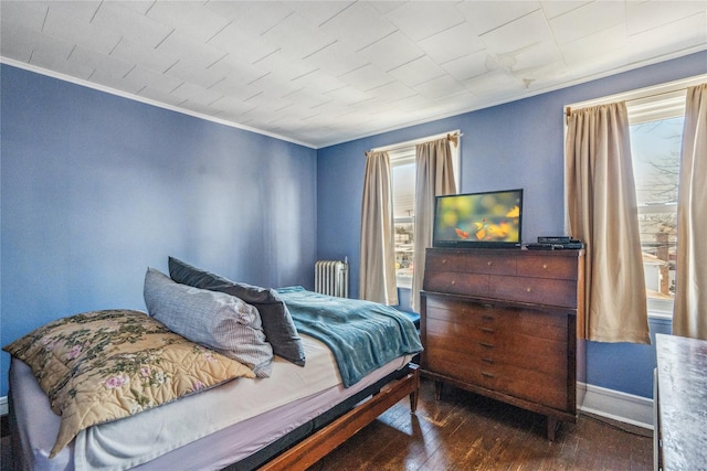 bedroom featuring hardwood / wood-style flooring, radiator, crown molding, and baseboards