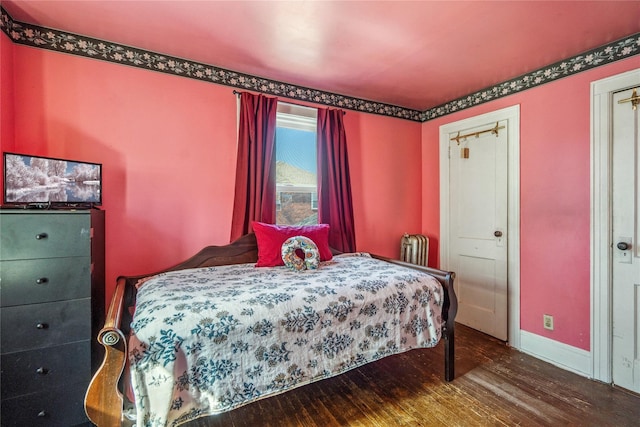 bedroom with baseboards, radiator, and wood finished floors