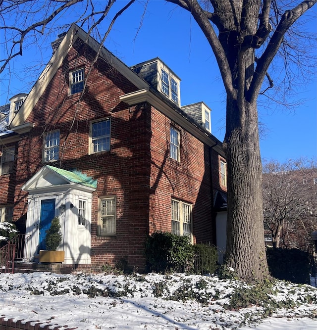 view of snowy exterior featuring brick siding