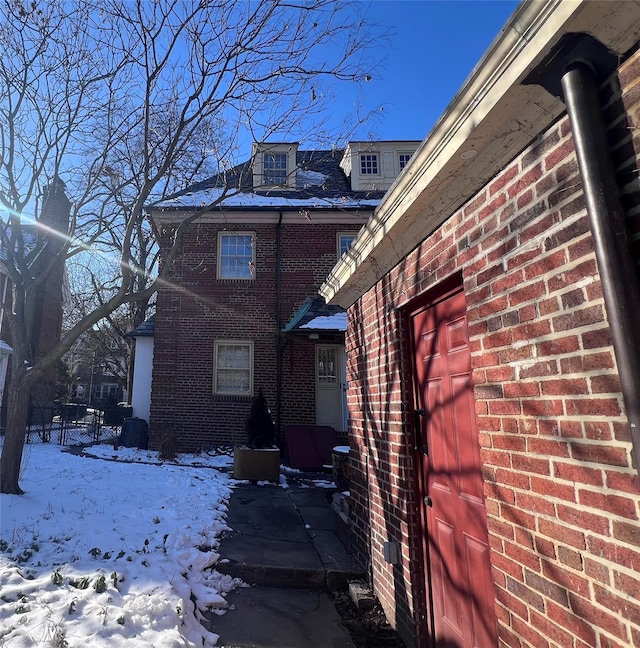 view of snowy exterior with brick siding