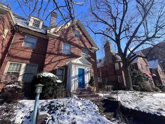 view of front of home with brick siding, central air condition unit, and a chimney