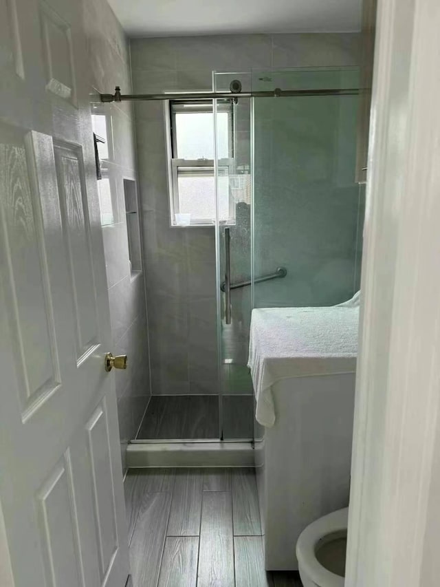 bathroom featuring a shower stall, toilet, and wood finished floors