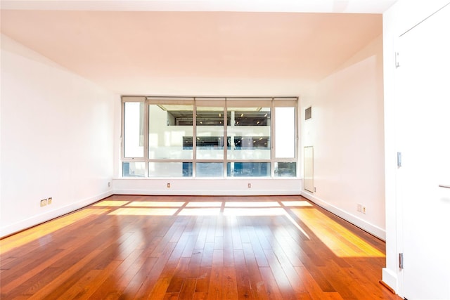 spare room featuring baseboards and hardwood / wood-style flooring