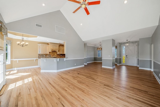 unfurnished living room featuring visible vents, baseboards, light wood-type flooring, and ceiling fan with notable chandelier