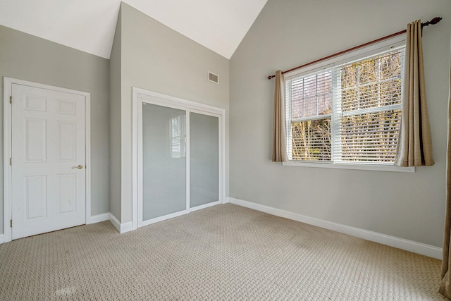 unfurnished bedroom featuring visible vents, baseboards, carpet, and vaulted ceiling