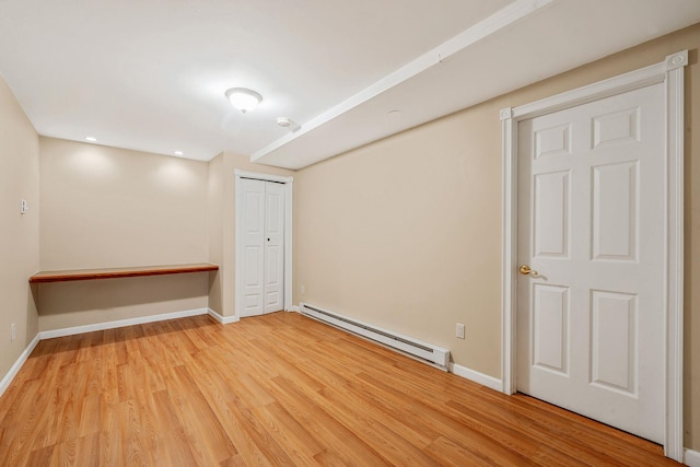 spare room with a baseboard radiator, wood finished floors, and baseboards