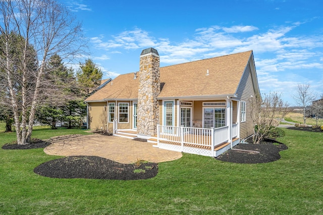 rear view of property with a shingled roof, a lawn, and a chimney