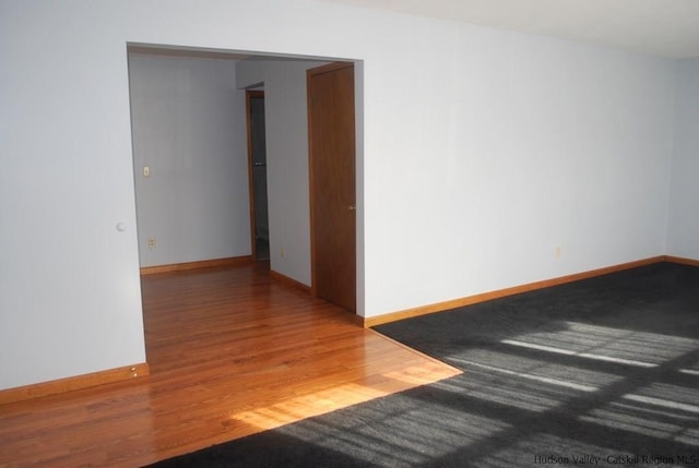 empty room with baseboards and wood finished floors