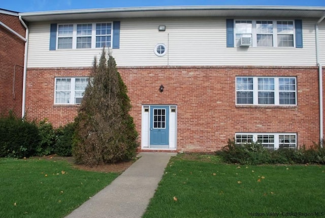 view of front facade with a front lawn, cooling unit, and brick siding