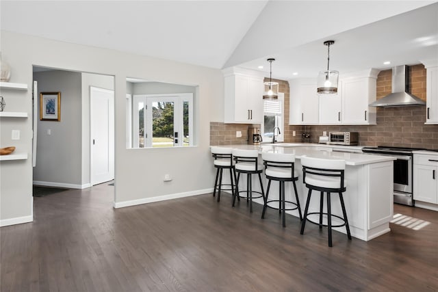 kitchen with electric range, plenty of natural light, a breakfast bar, and wall chimney exhaust hood