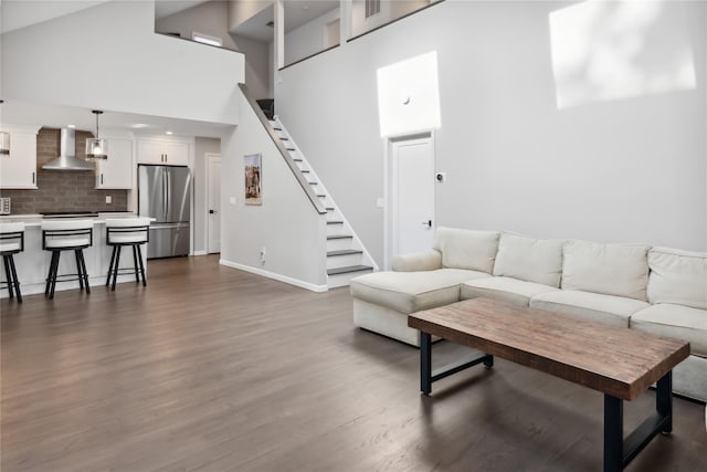 living area with dark wood finished floors, stairway, baseboards, and a towering ceiling