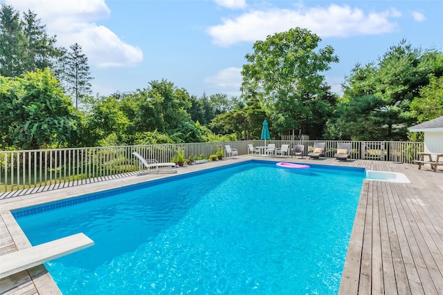 view of swimming pool with a diving board, a fenced in pool, and a deck