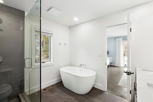 full bath with vanity, a wealth of natural light, a shower stall, and a freestanding bath