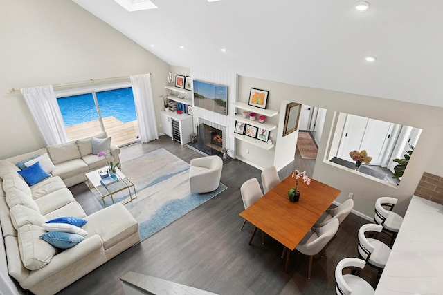 living room with baseboards, wood finished floors, recessed lighting, a lit fireplace, and lofted ceiling with skylight