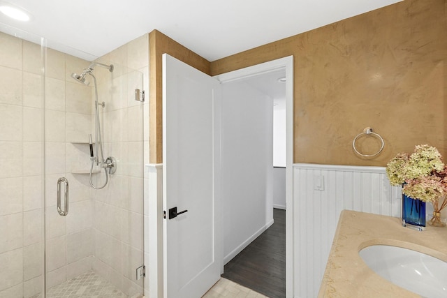 bathroom featuring a shower stall, wainscoting, and a sink