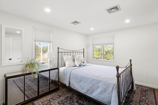 bedroom with visible vents, multiple windows, and wood finished floors