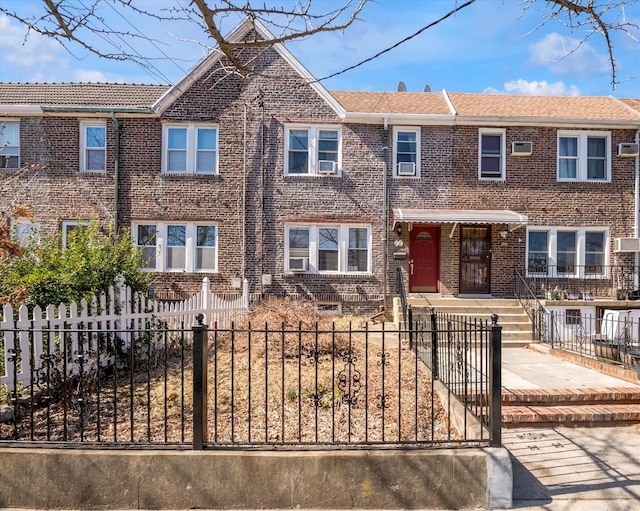 townhome / multi-family property with a fenced front yard and brick siding