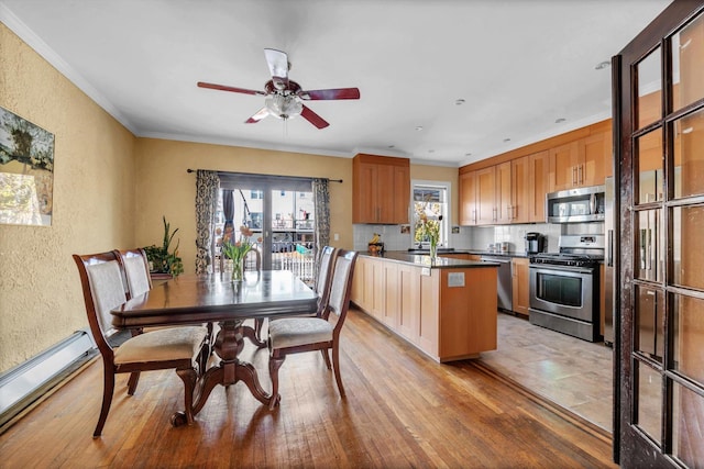 kitchen featuring a baseboard heating unit, ornamental molding, a textured wall, and stainless steel appliances