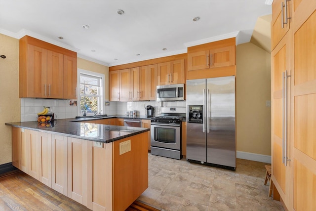 kitchen with tasteful backsplash, dark stone counters, appliances with stainless steel finishes, a peninsula, and baseboards