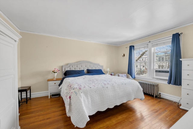 bedroom featuring crown molding, radiator heating unit, wood finished floors, and baseboards